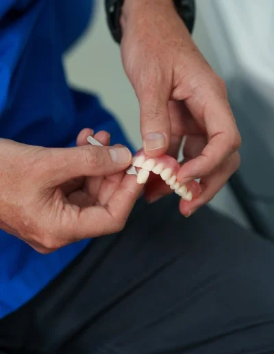 Hands adjusting a removable denture during a fitting demonstration.