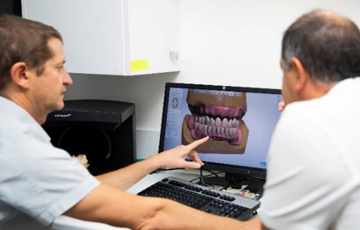 digital-denture-treatment-planning Dr Pierre and Dr André reviewing a 3D digital denture model on a computer during treatment planning