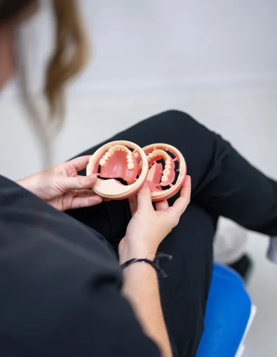 Person holding upper and lower denture models during a dental consultation
