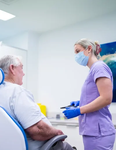 Dr Mills speaking with a patient in the treatment room at Custom Denture Clinic