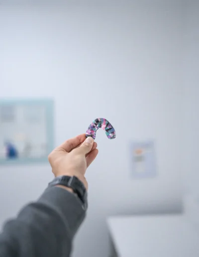 Custom-made colourful dental appliance held during a consultation at Custom Denture Clinic