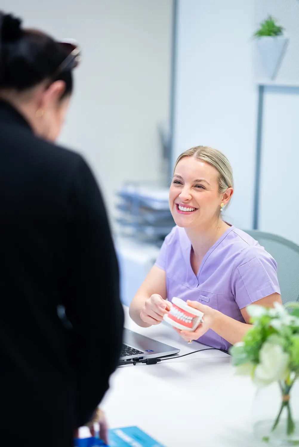 Custom Denture Clinic team member discussing a dental model with a patient